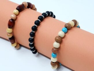 three neutral colored beaded bracelets on a peach roll of paper
