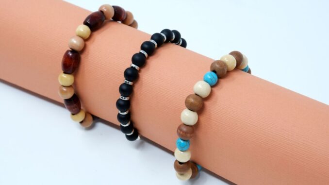 three neutral colored beaded bracelets on a peach roll of paper